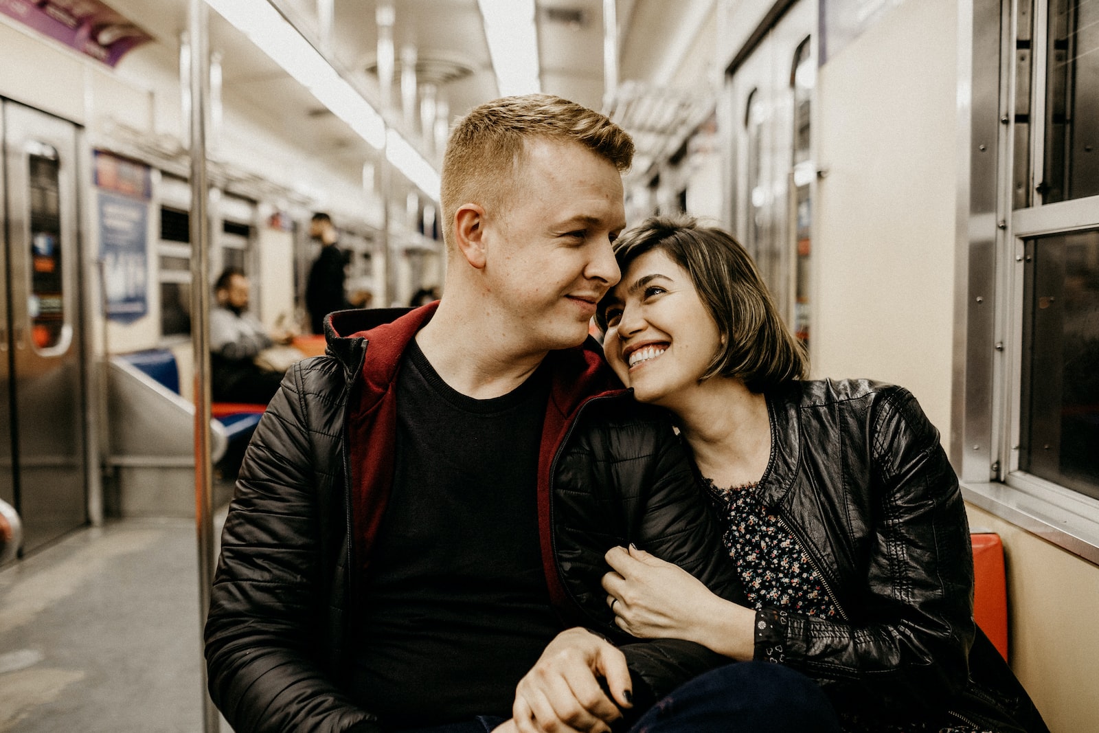 woman hugging man while sitting inside train