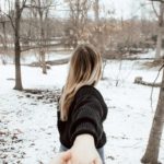 woman in black sweater standing on snow covered ground during daytime
